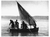 A early photo taken at daybreak on the Sea of Galilee. The boatmen handle long drag nets, put out at night, usually on deep water.